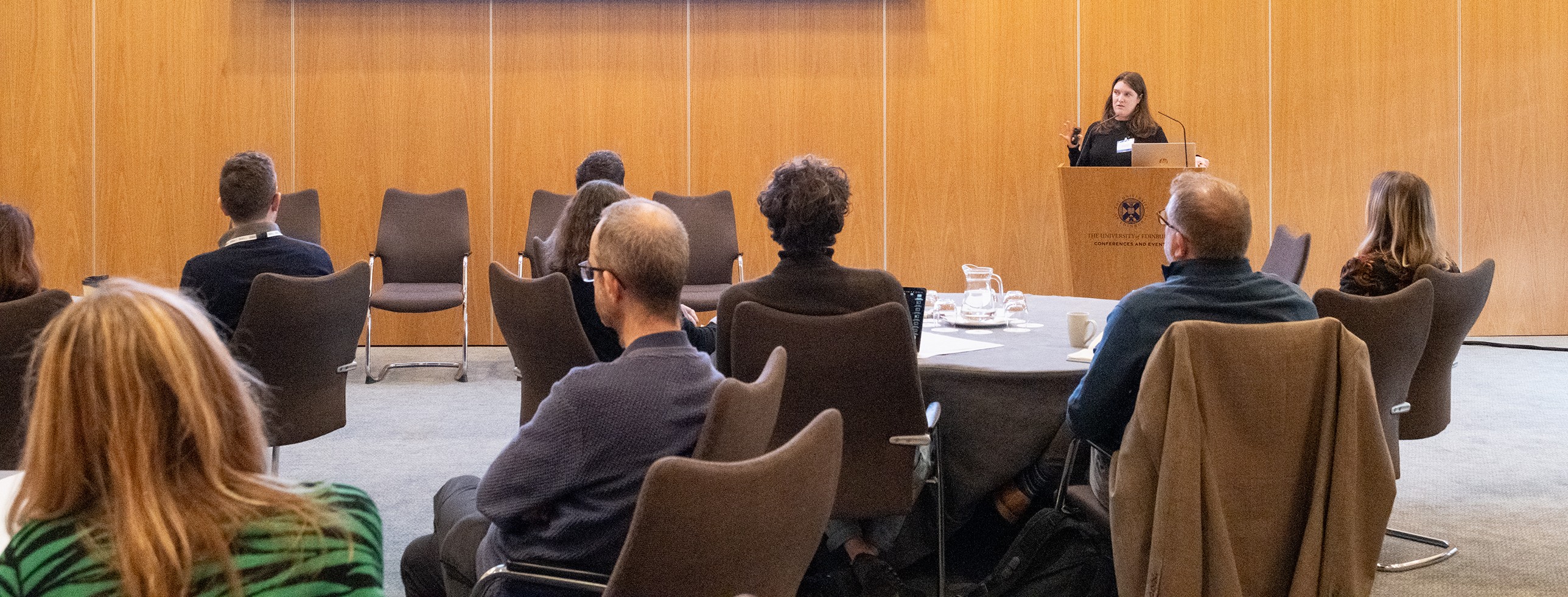 People writing on a piece of poster paper during a conference session. 